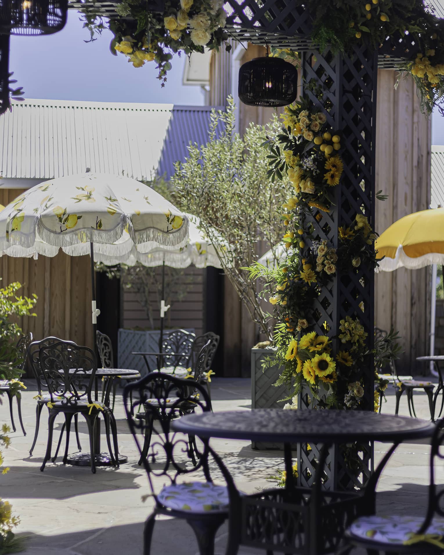 The Amalfi Garden with yellow flowers and tables and chairs with umbrellas.