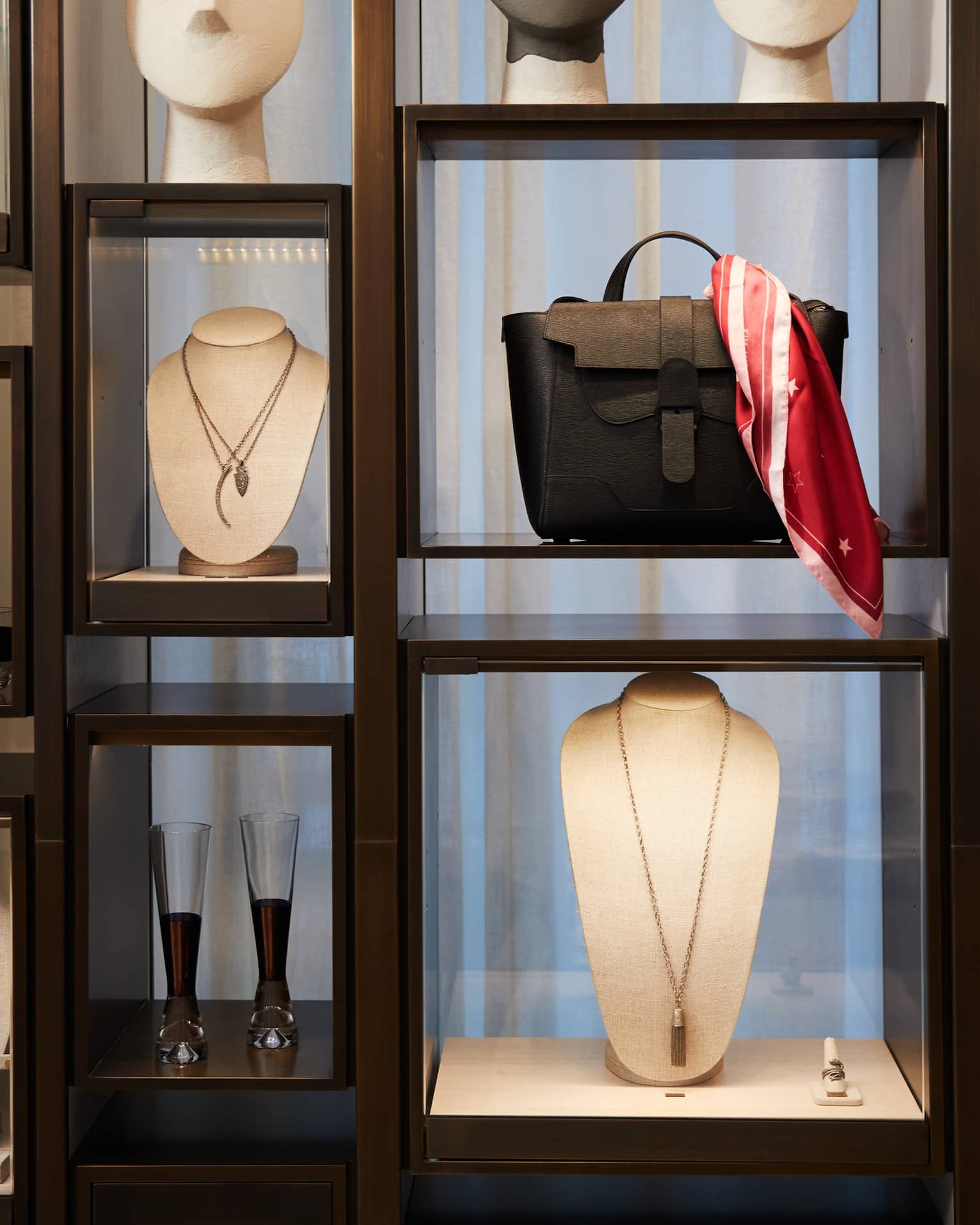 Boutique retail store shelf with designer necklaces, handbag, cocktail glasses 