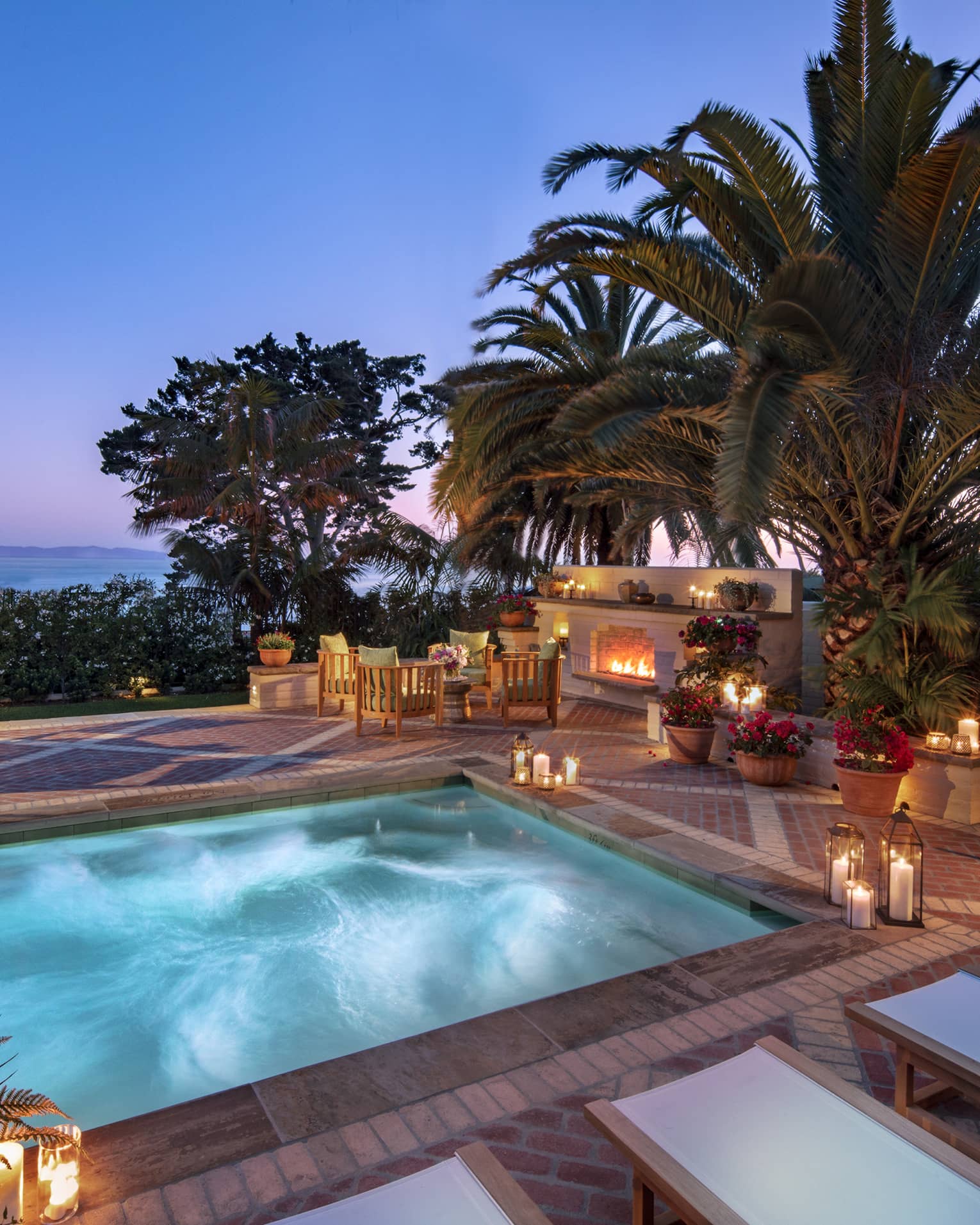 Illuminated villa plunge pool and patio, palm trees at dusk