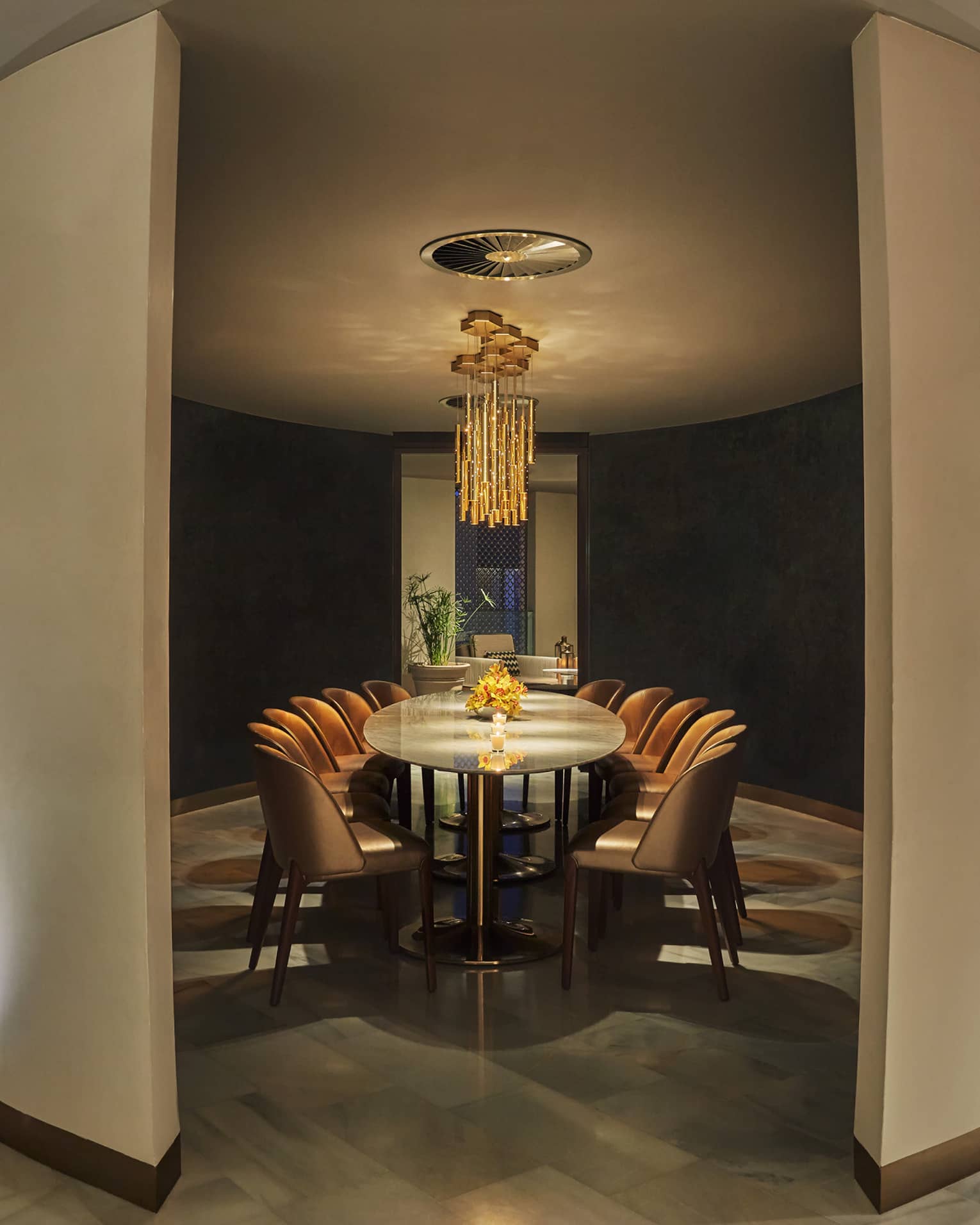 Modern private dining table for 12 within curved dividers, under modern orange chandelier 