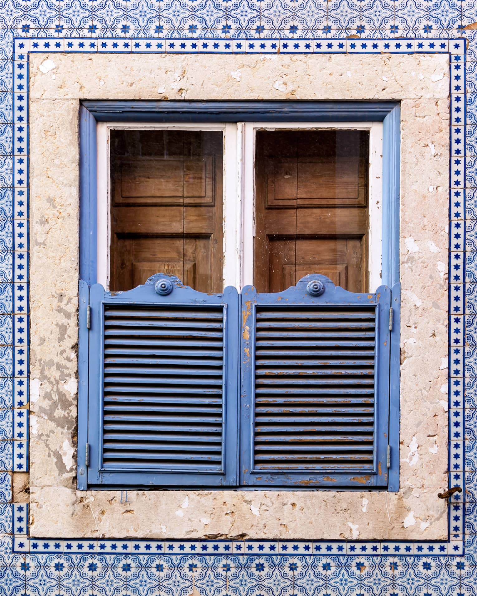 A blue wall and window covered in blue and brown doors.