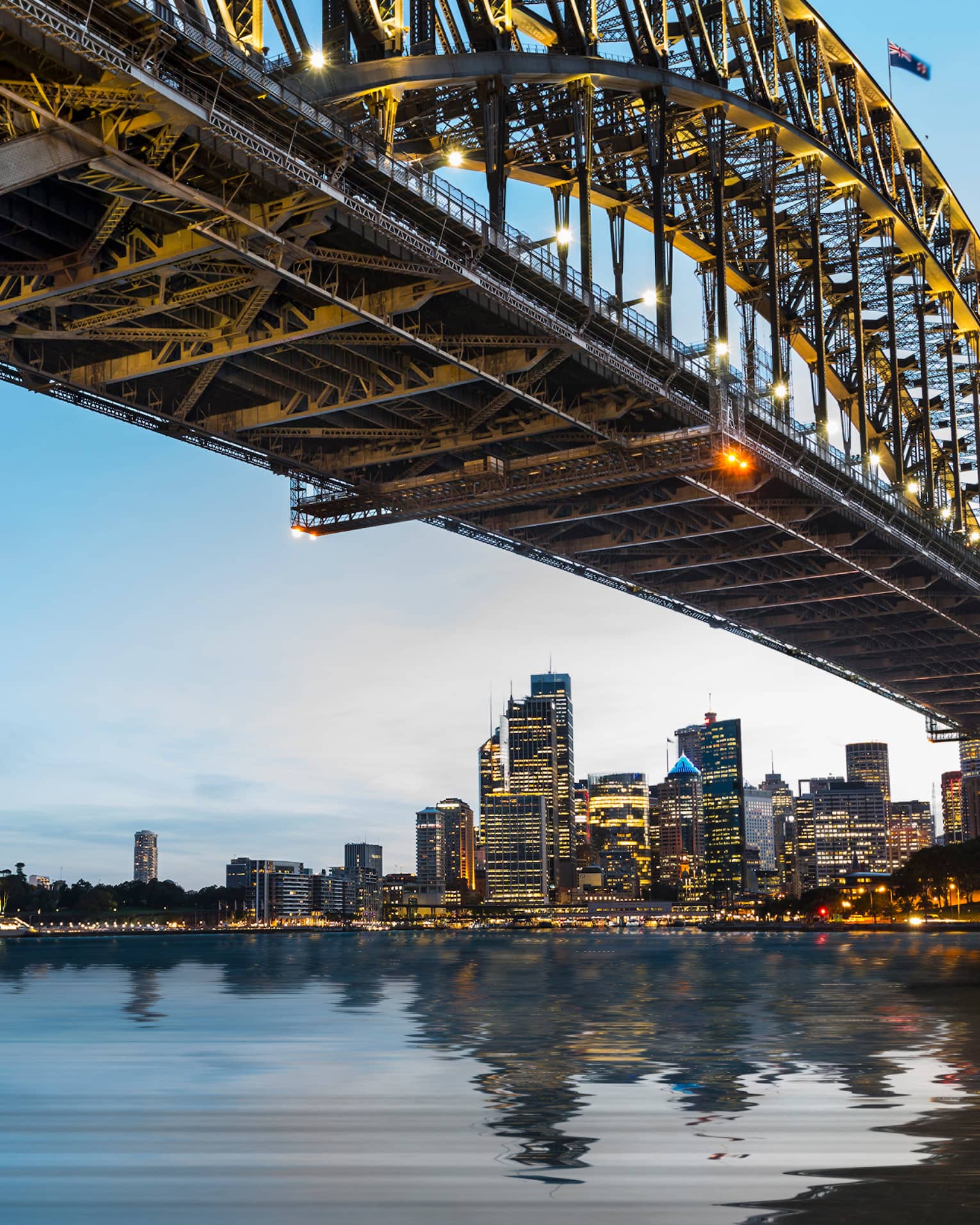 View from under bridge to Sydney waterfront skyline, lights at dusk