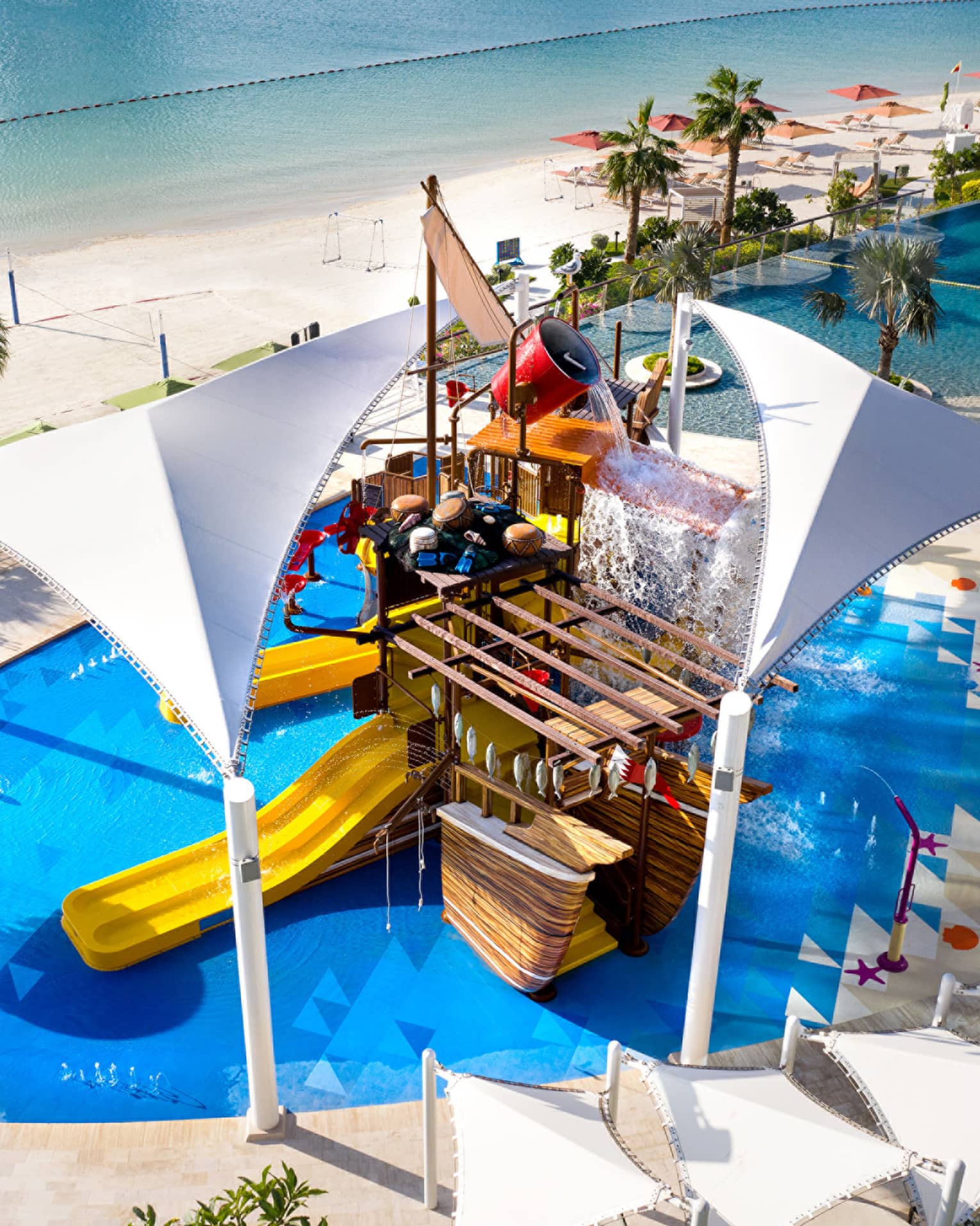 A large orange waterslide built into a faux pirate ship descending into a crystal blue pool of water.