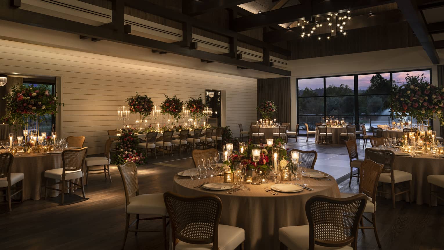 Banquet tables set for wedding in dimly lit barn