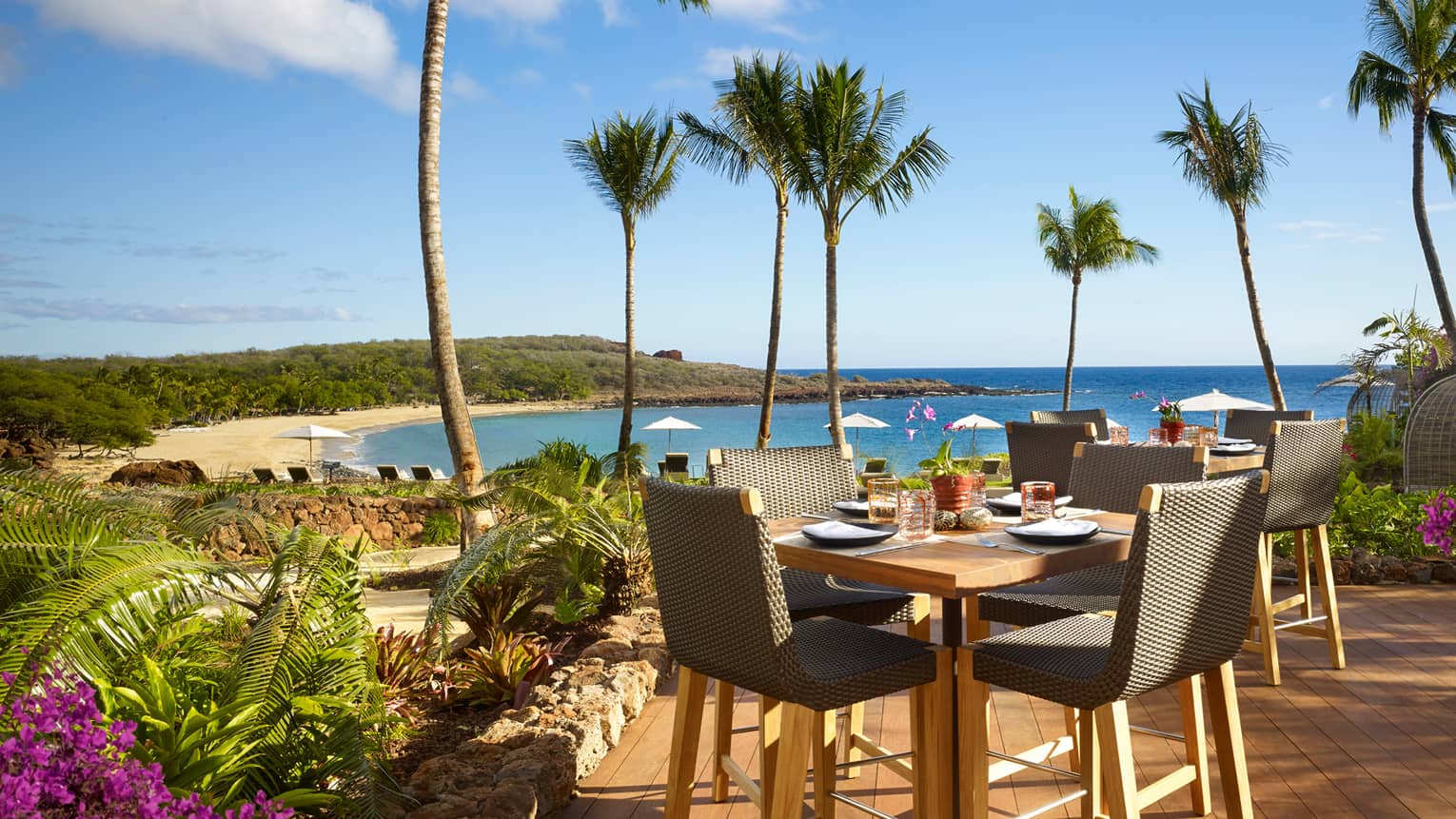 Malibu Farm Bar dining table, chairs on sunny patio overlooking beach, ocean
