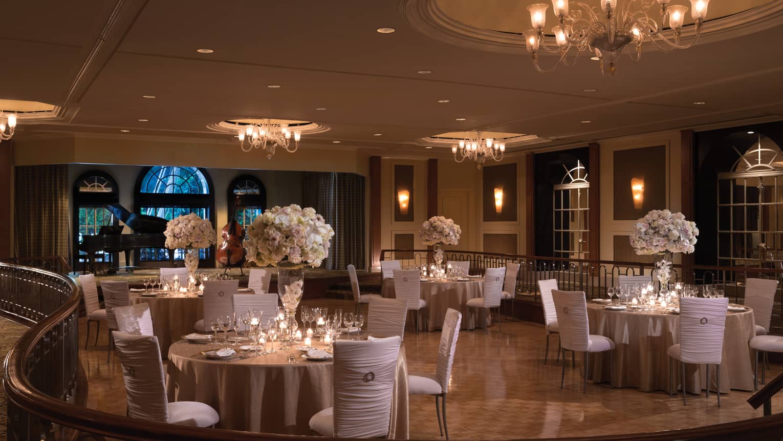 Elegant wedding reception tables with white chairs, flowers on ballroom floor