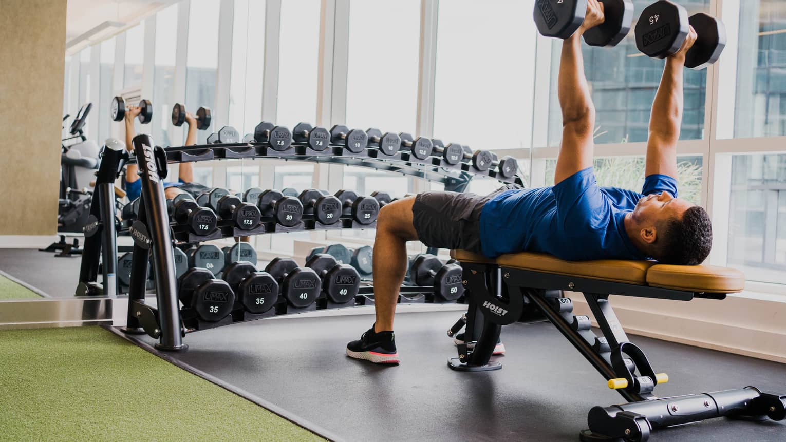 A man lifting two weight while laying on a bench.