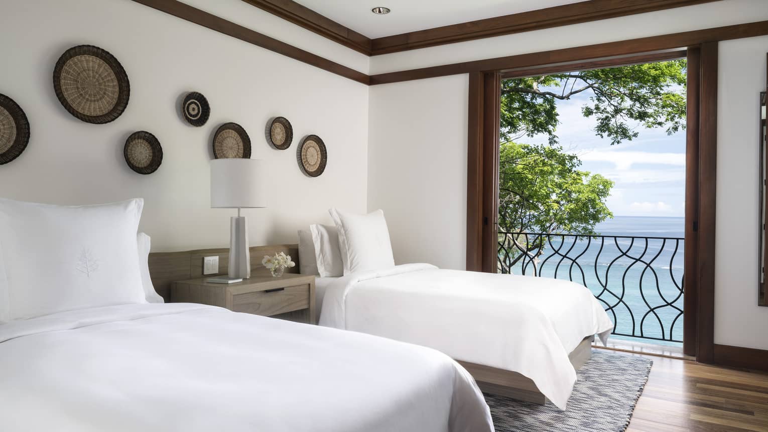 Twin beds with white linens beside open door to iron terrace, ocean views 