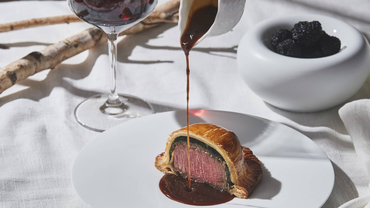 Beef Wellington dish with gravy sauce, fine dining restaurant table