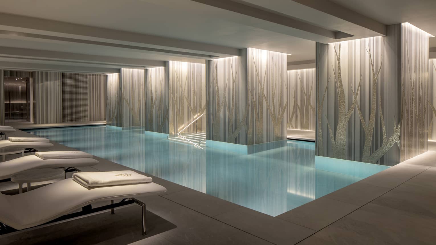 View of indoor serenity pool with illuminated classic columns and blue water