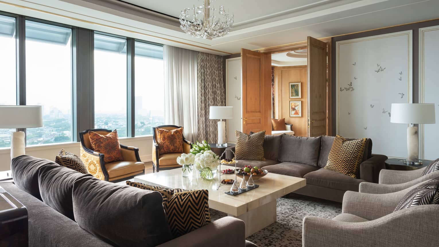 Hotel suite seating area with two plush sofas and four armchairs by sunny window