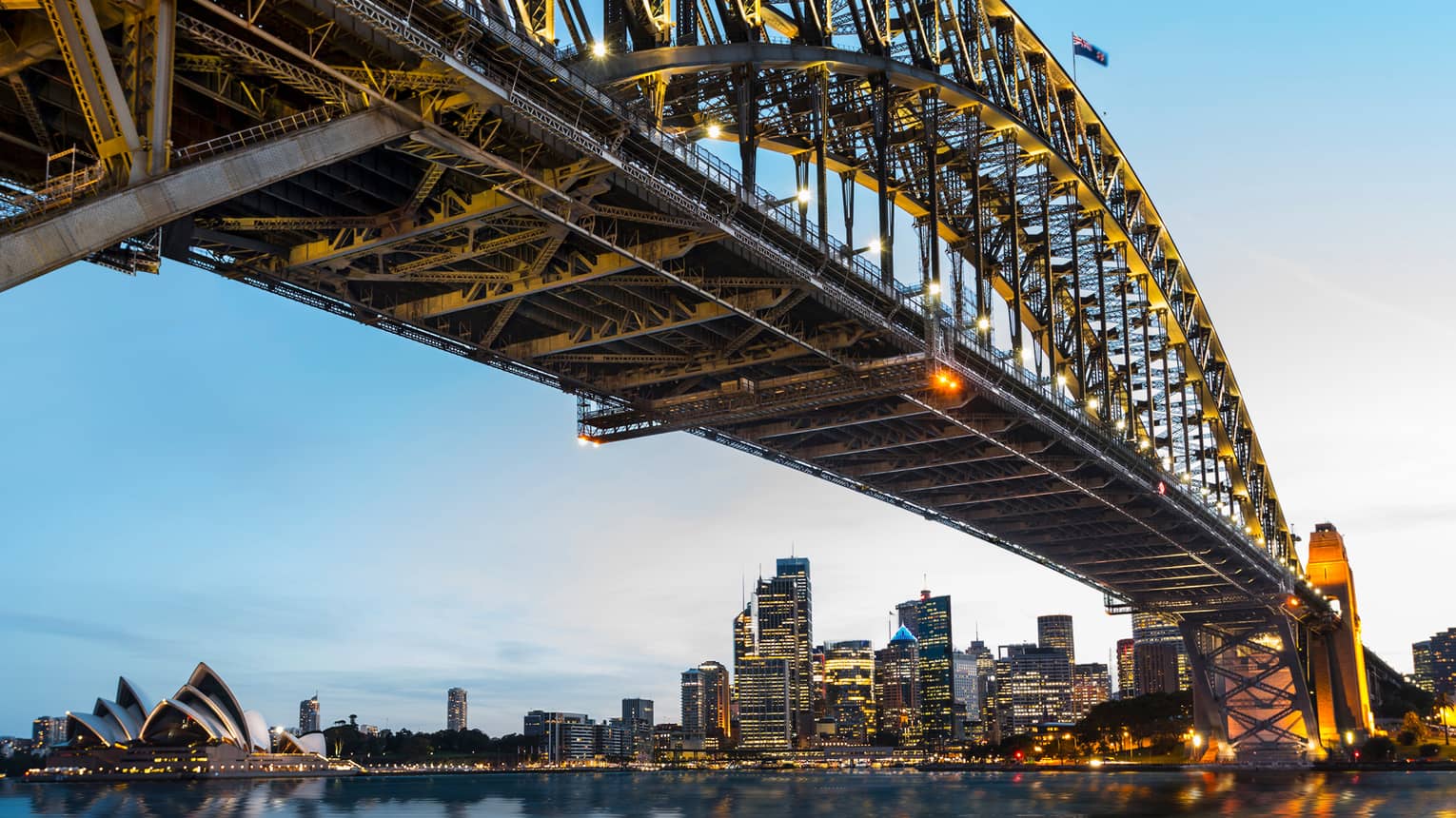 View from under bridge to Sydney waterfront skyline, lights at dusk