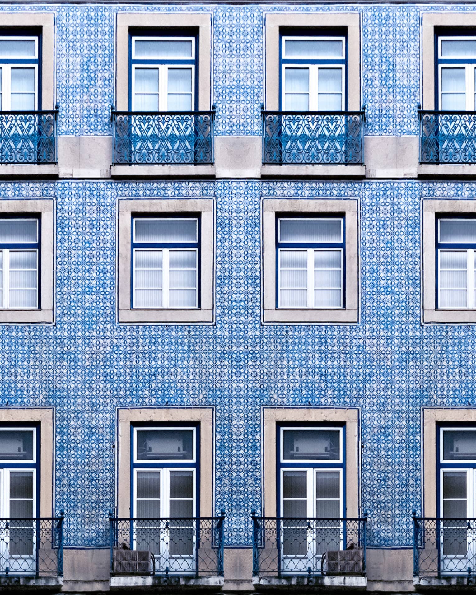 A blue tiled wall with many windows and balconies.