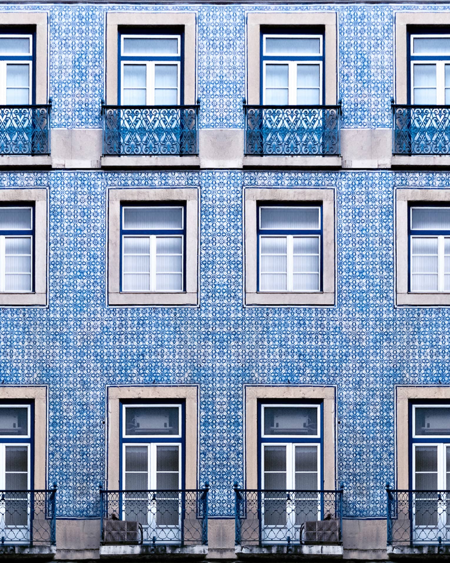 A blue tiled wall with many windows and balconies.