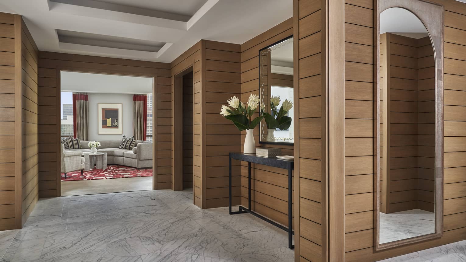 Suite entryway with wood-panelled walls and marble floors leading to living area at Four Seasons