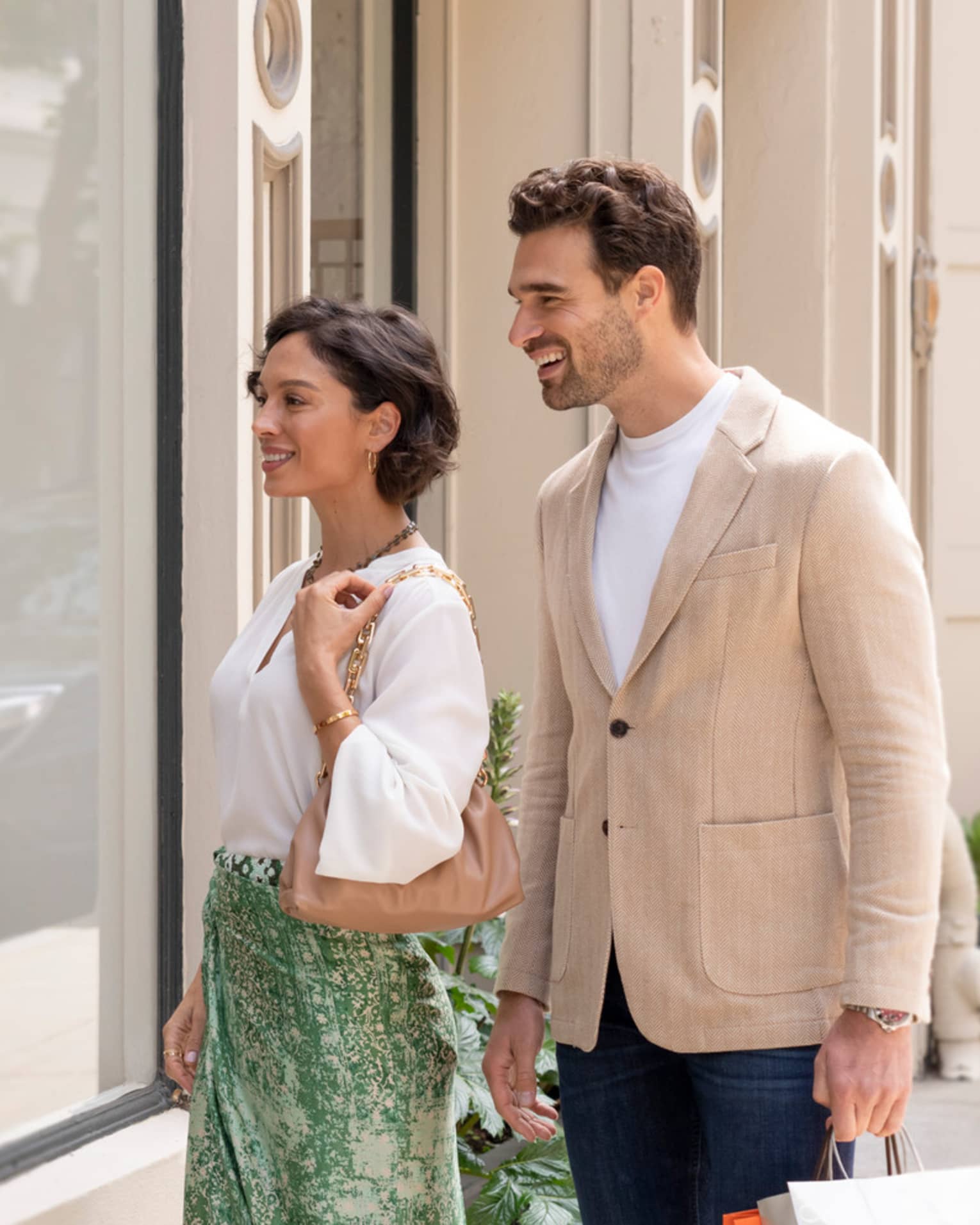 A couple admires a storefront together while shopping. 