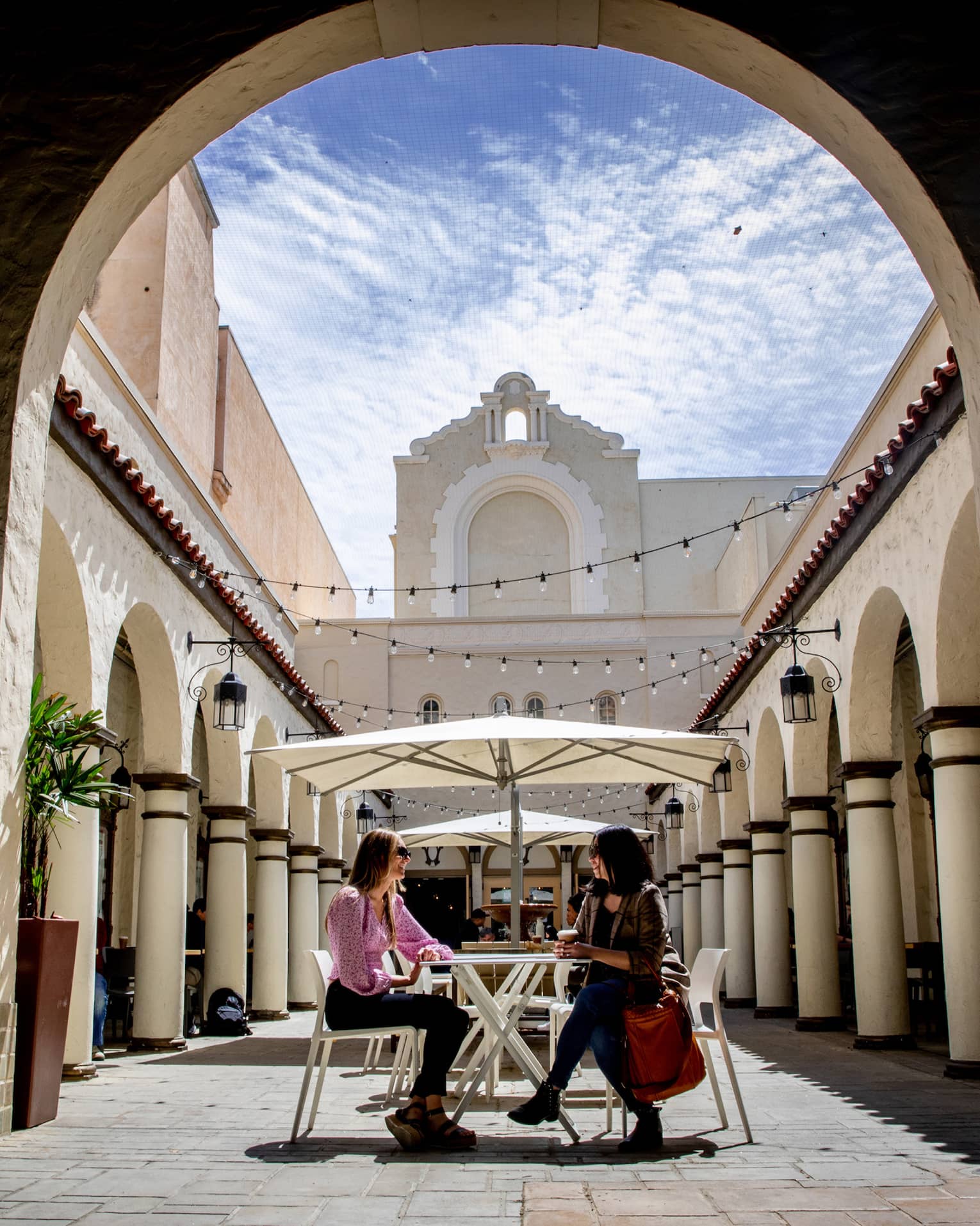 Two people sitting outside under an archway.