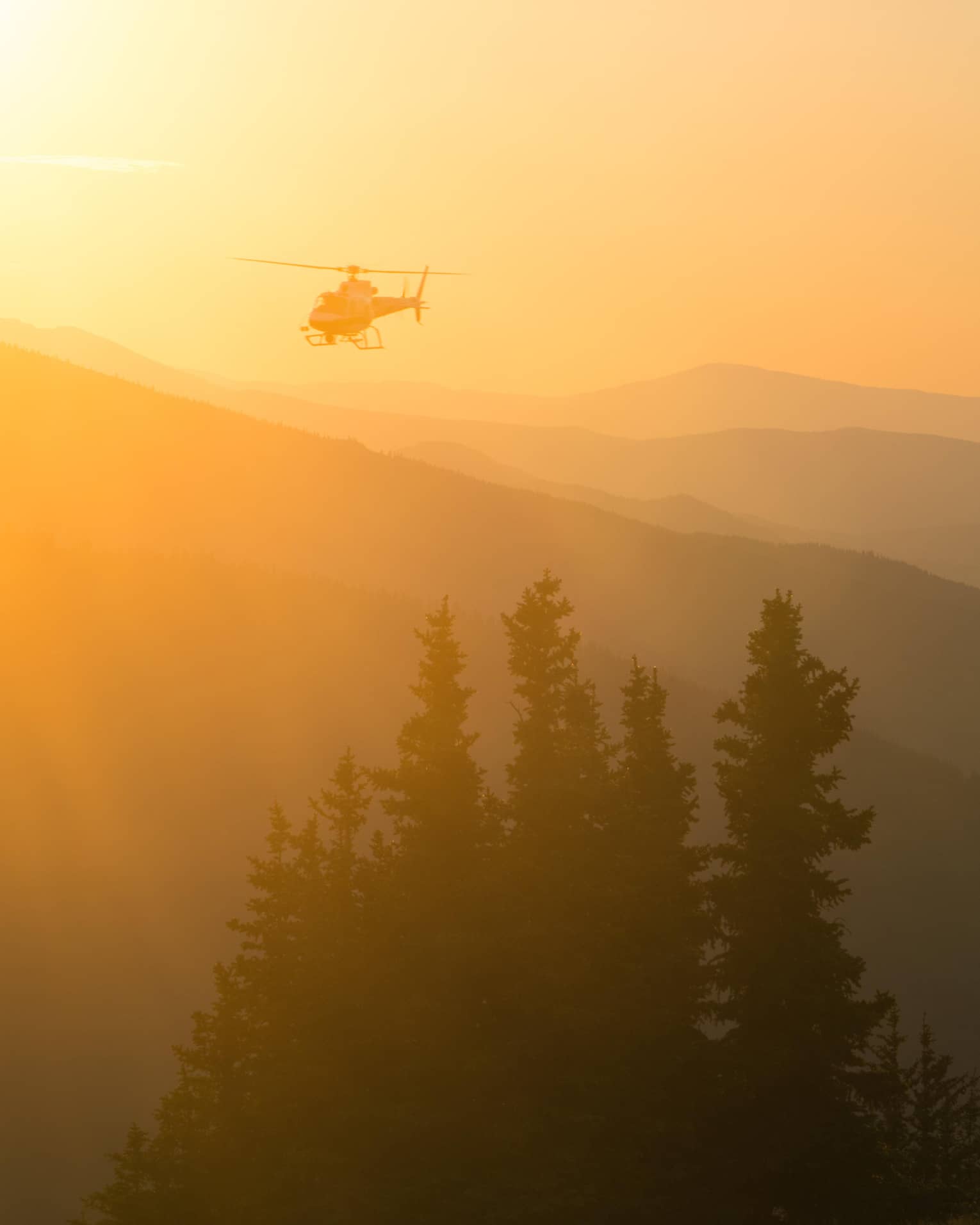 Helicopter at sunset flying over Aspen Mountain in the Elks Mountain range