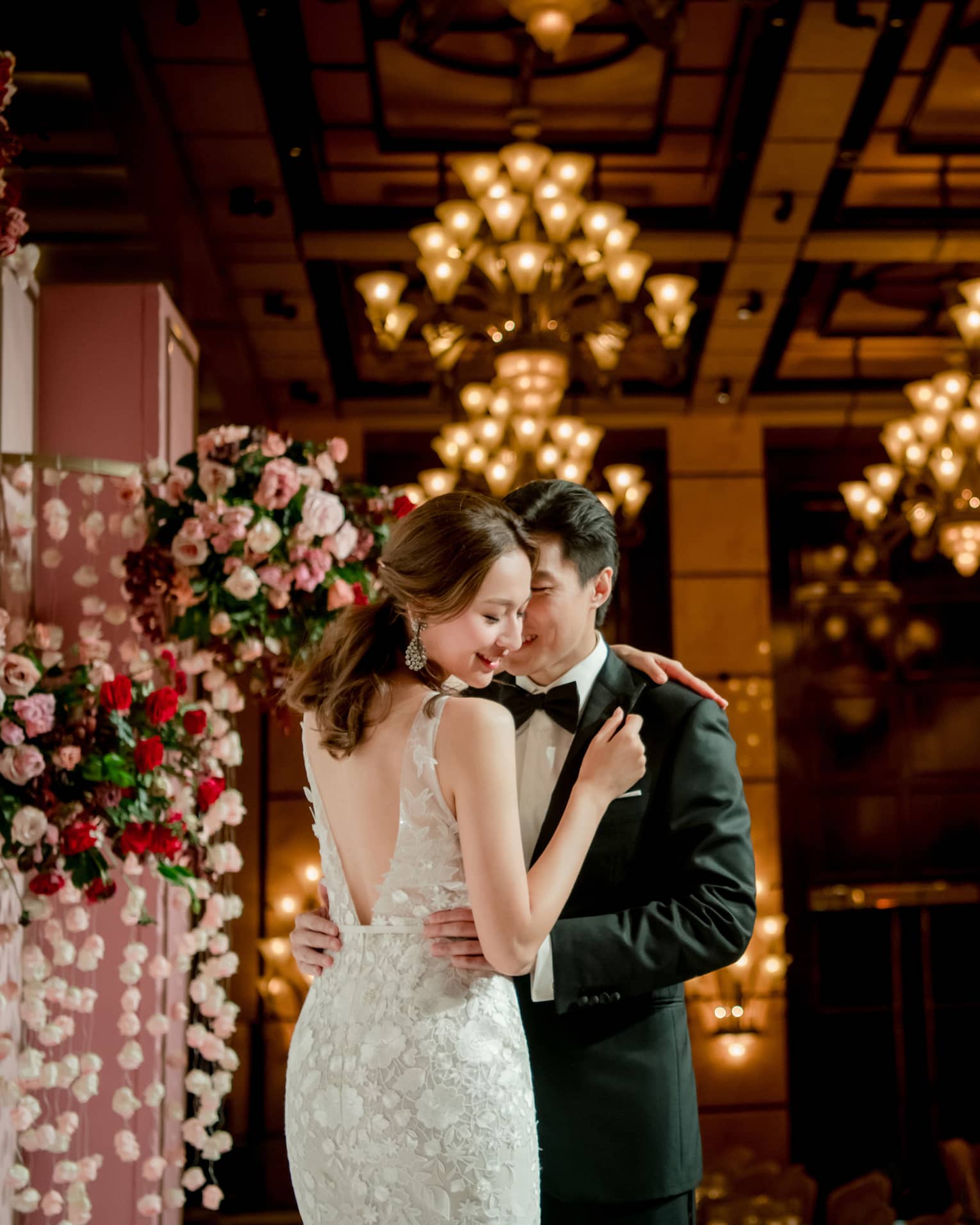 Bride and groom embrace at wedding ceremony in banquet room with lights