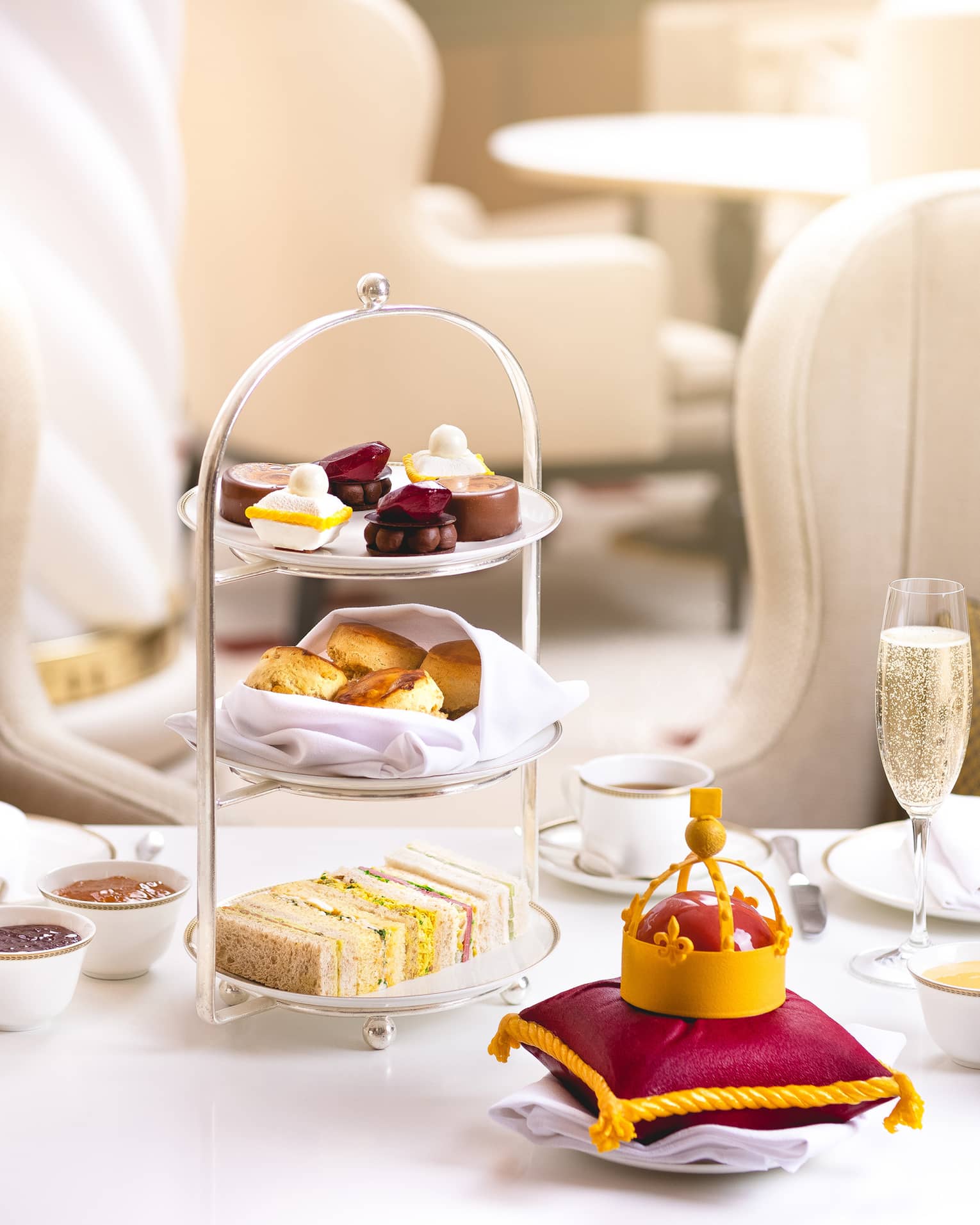Crown Jewels-themed Afternoon Tea spread with a small replica crown on a burgundy pillow