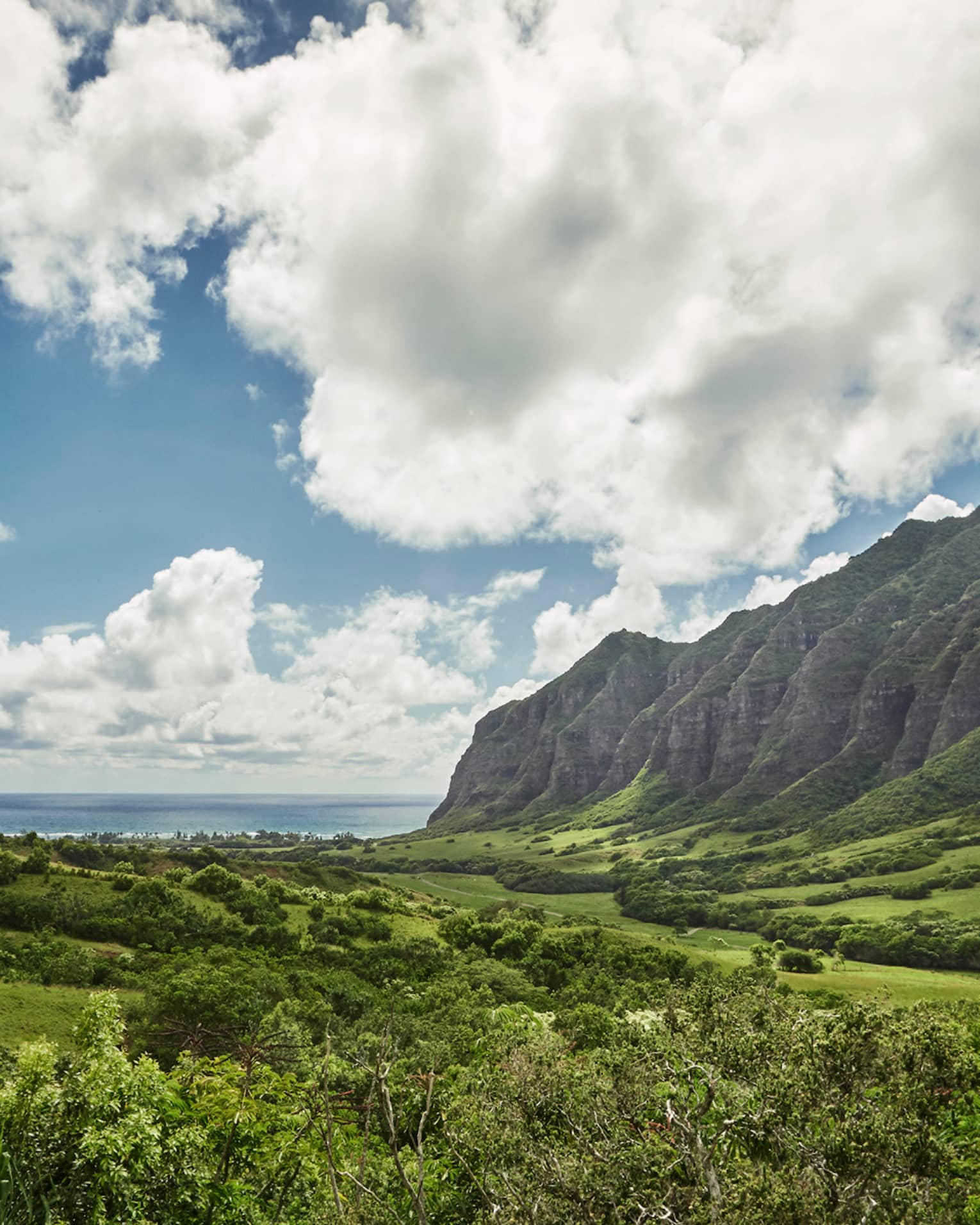 Oahu sweeping green cliffs, mountains, under blue skies