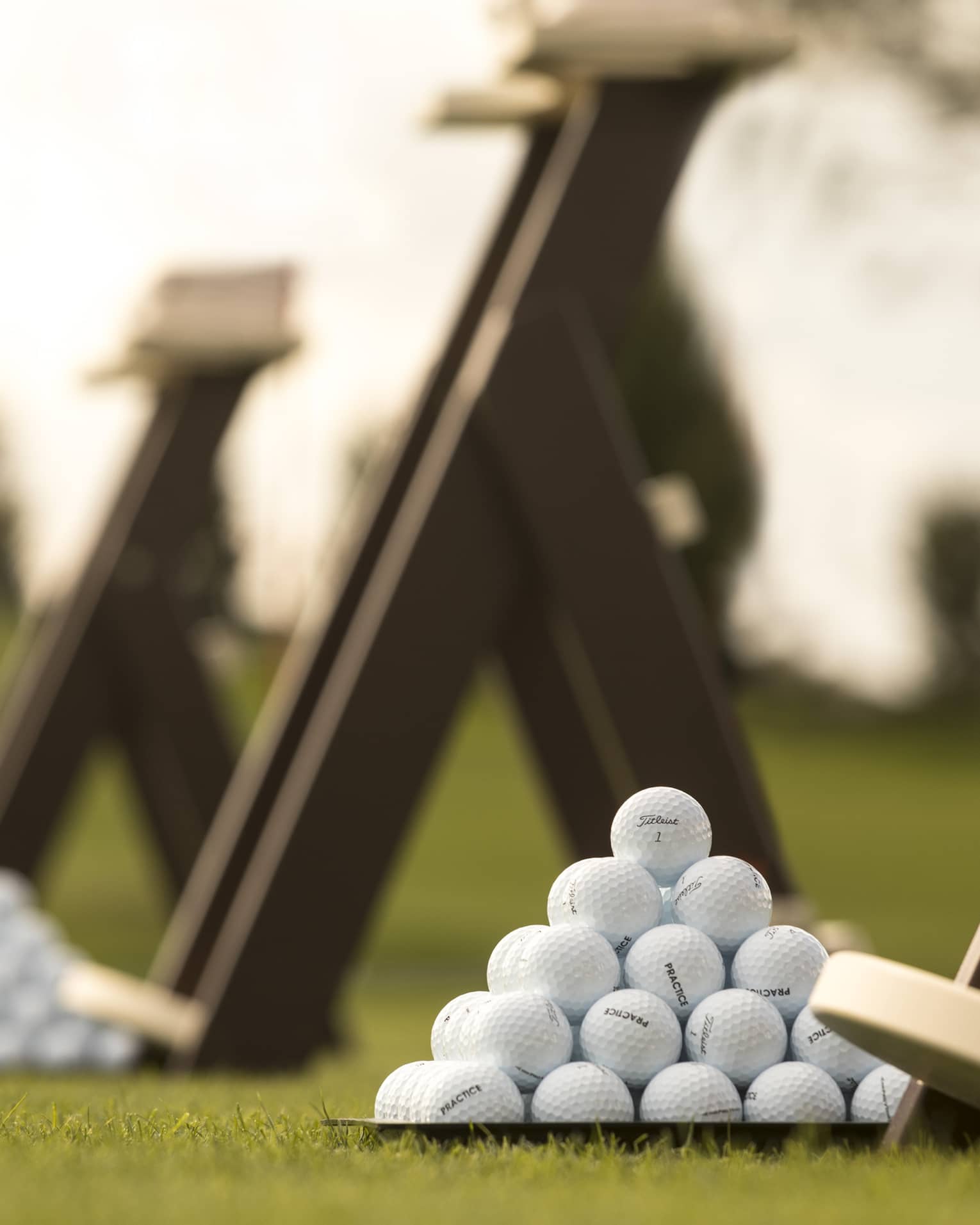 Stacks of white golf balls on lawn in front of wood panels