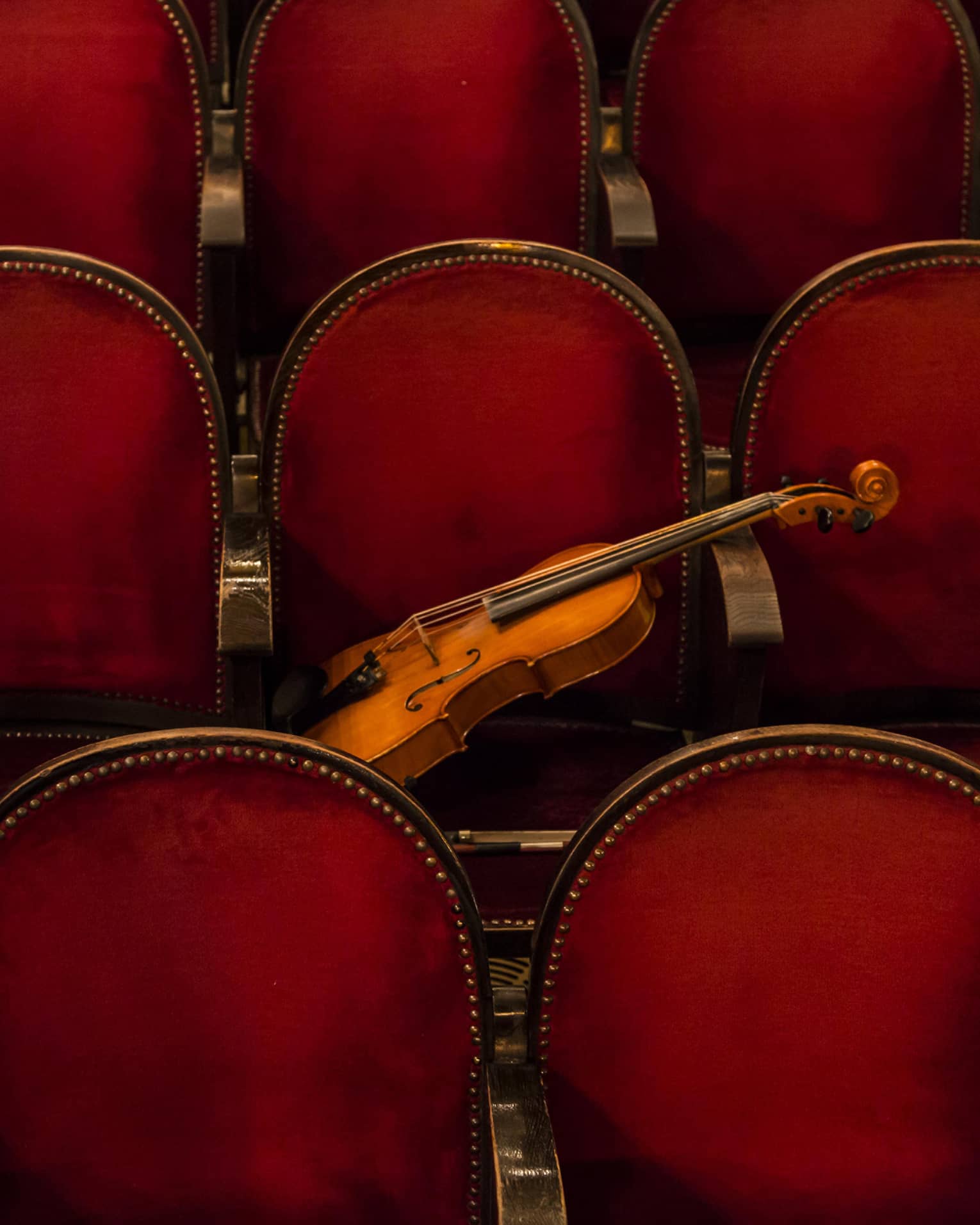 Red theatre chairs with a violin resting on one.