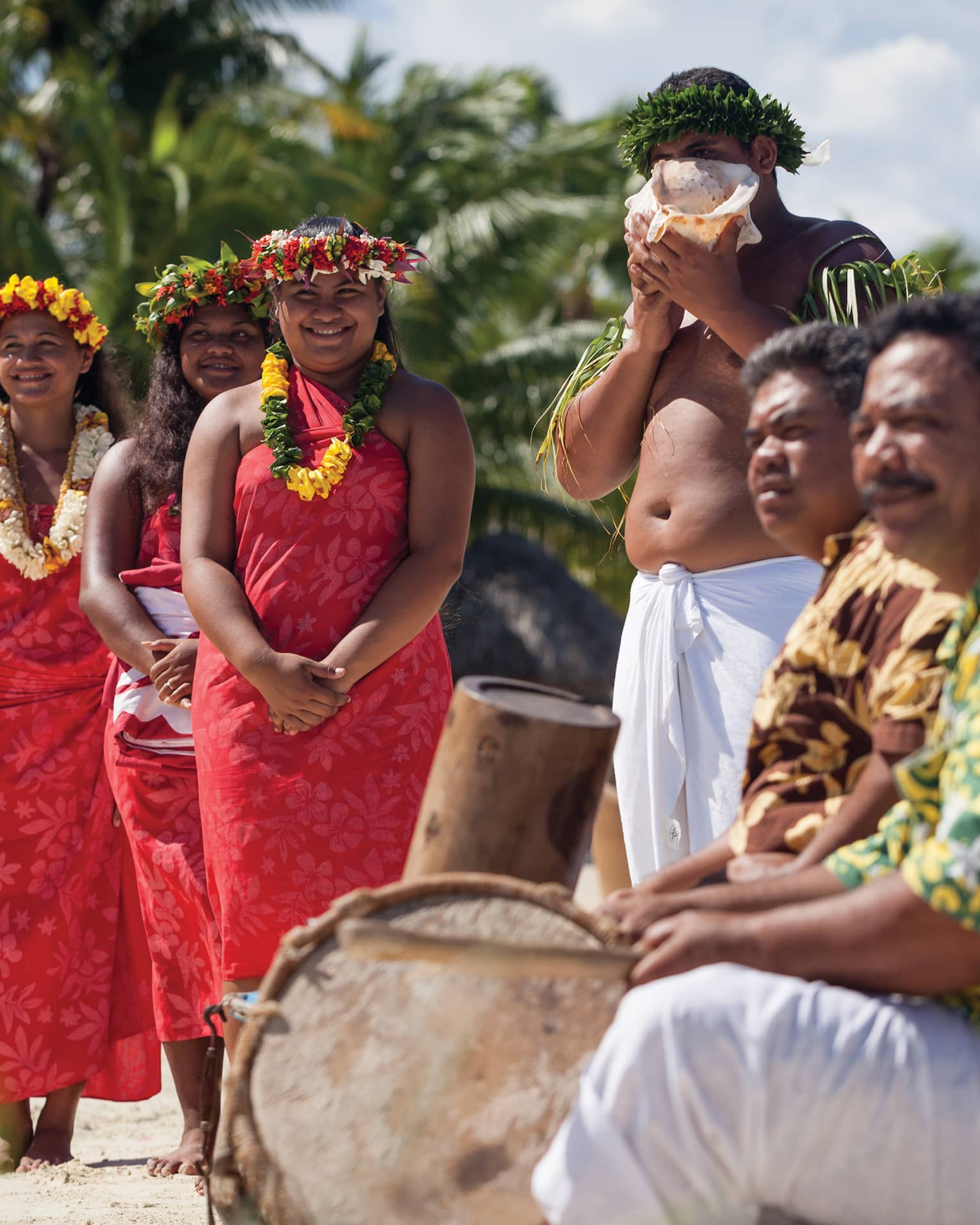 Polynesian wedding ceremony, guests wearing traditional clothing, man with shell