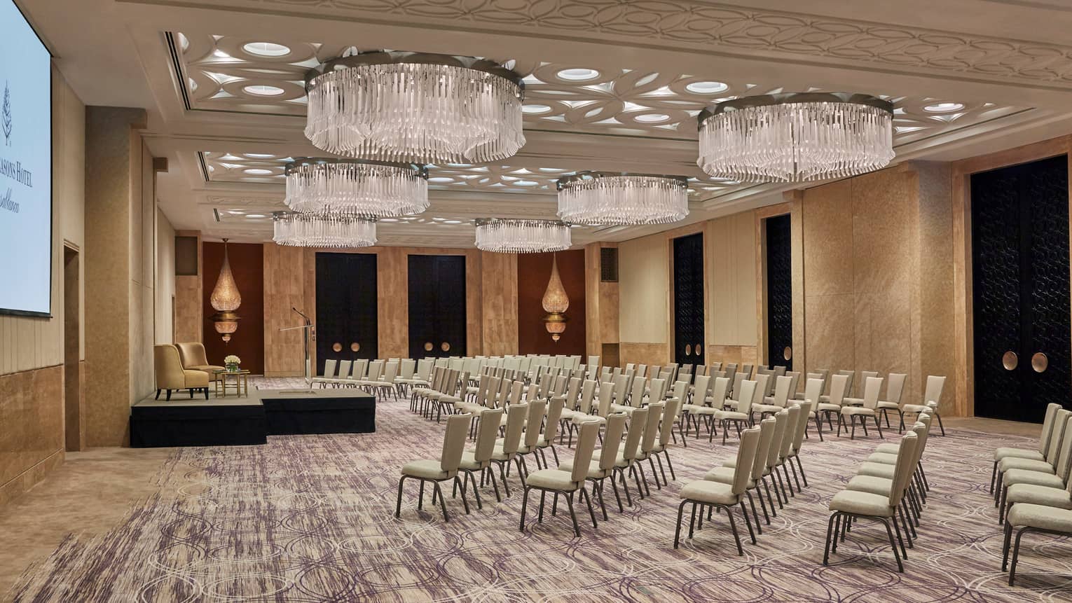 Rows of chairs face small stage in Atlantique ballroom with large chandeliers 