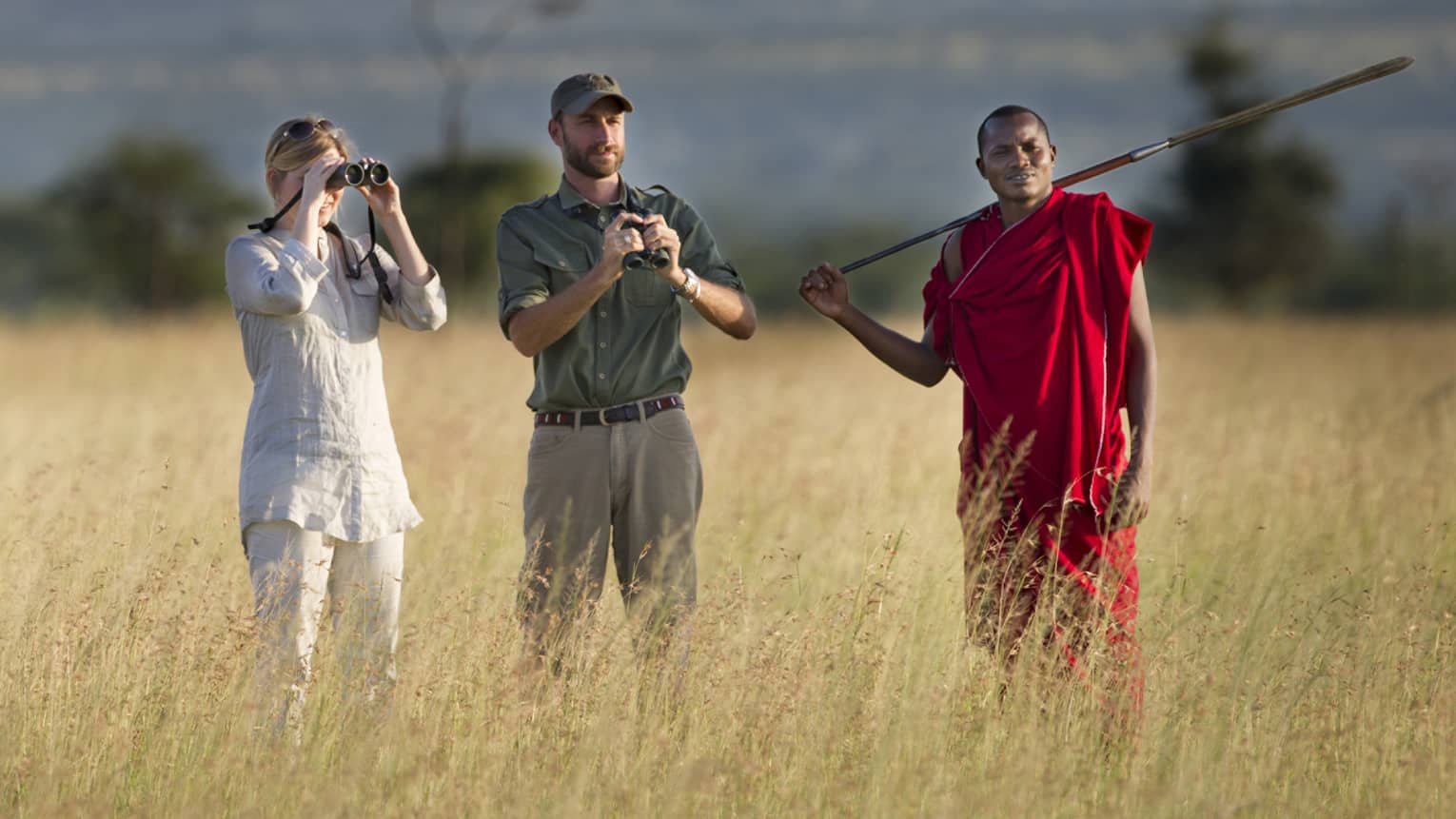 Couple takes photos on walking safari through tall grass with guides