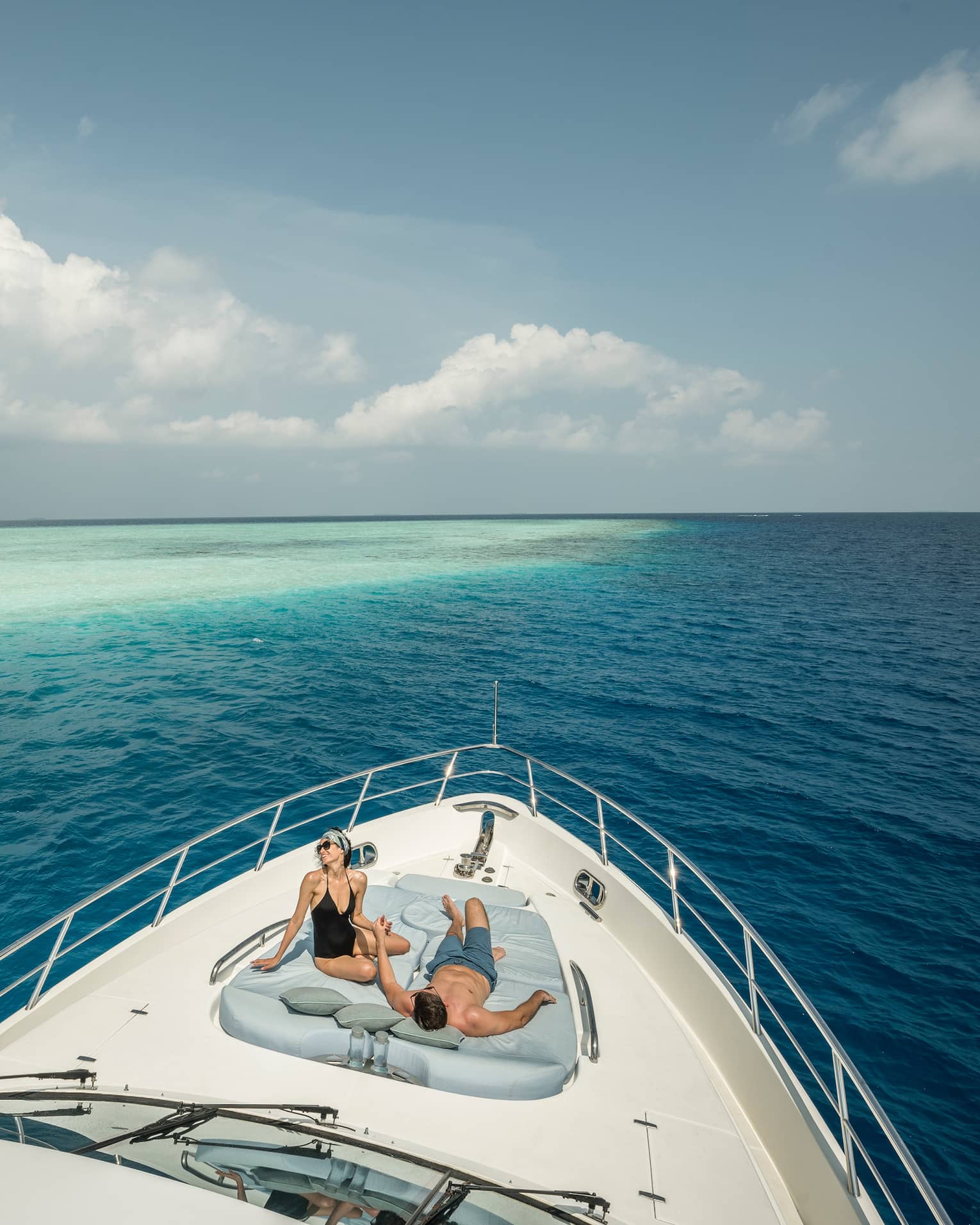 Couple lounge on cushions at front of Voavah Summer private yacht on ocean