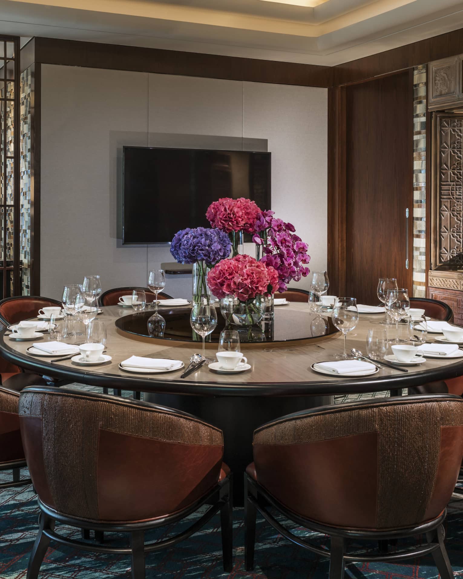 Leather bucket chairs around private meeting dining table, TV on wall