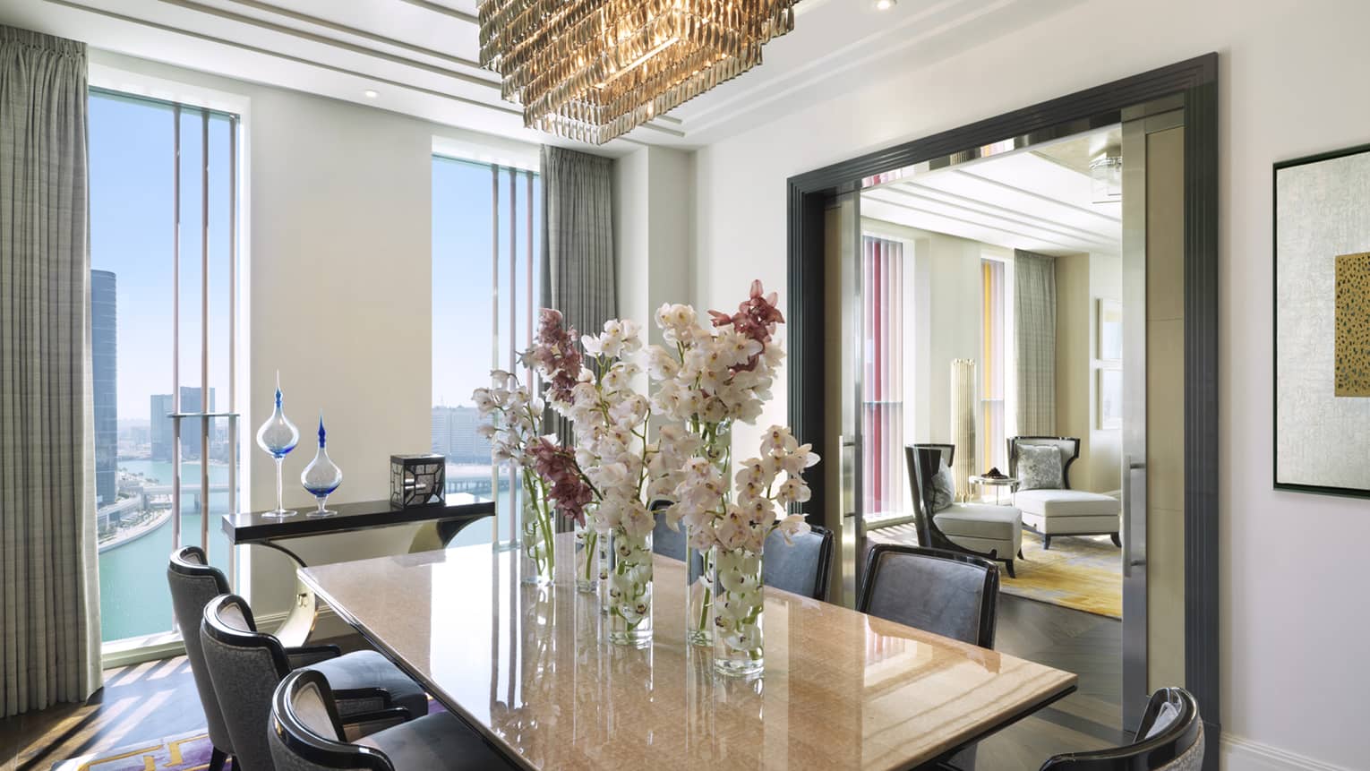 Vases with orchids on dining table by tall windows with gulf and skyline views 