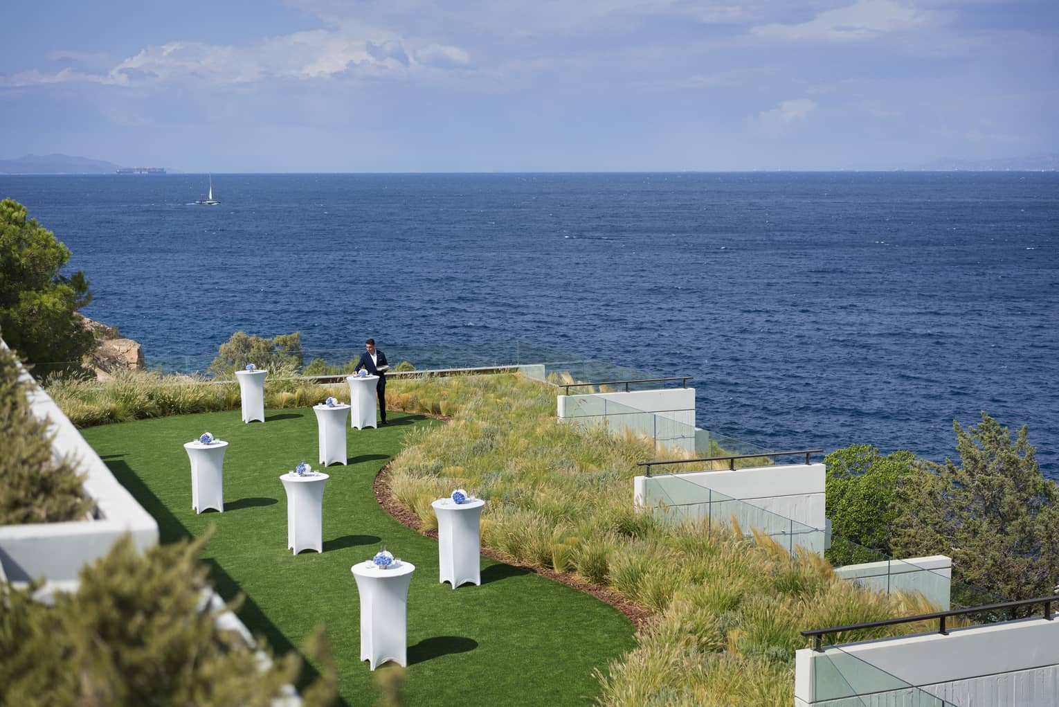 An attendant decorating tables on the Nafsika Platea outdoor event space, overlooking the sea.