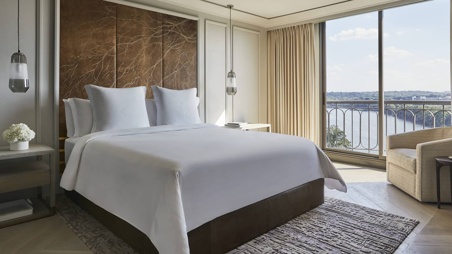 Governor's Suite hotel room bed under large leather headboard with branch pattern, large windows