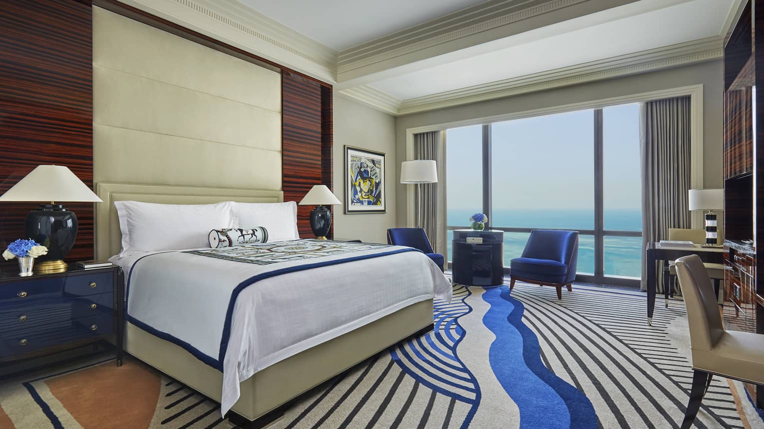 Premier Room bed with tall padded headboard, modern carpet with blue swirl design, floor-to-ceiling window with Arabian Gulf view