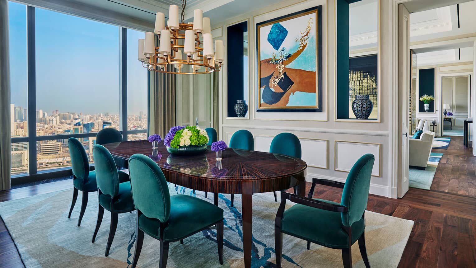 Hotel room 1930s-style 8-person dining room table with maritime green velvet chairs, chandelier, window with city view