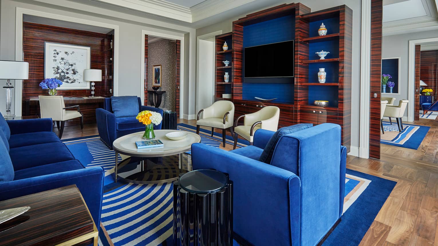 State Suite living room with plush blue sofa, armchairs, round coffee table, TV wall cabinet 