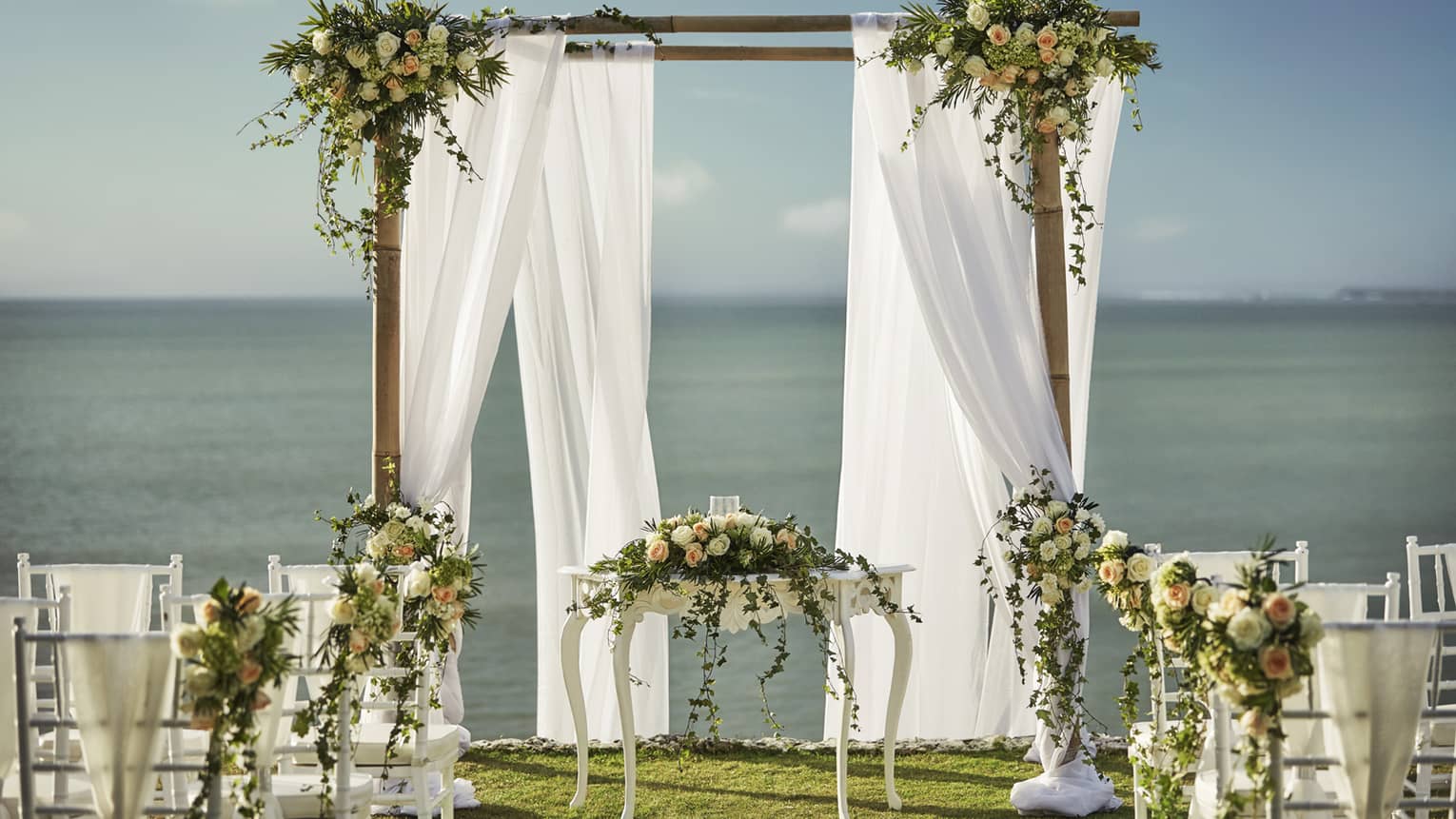 Outdoor wedding reception, altar with white curtains and flowers near ocean