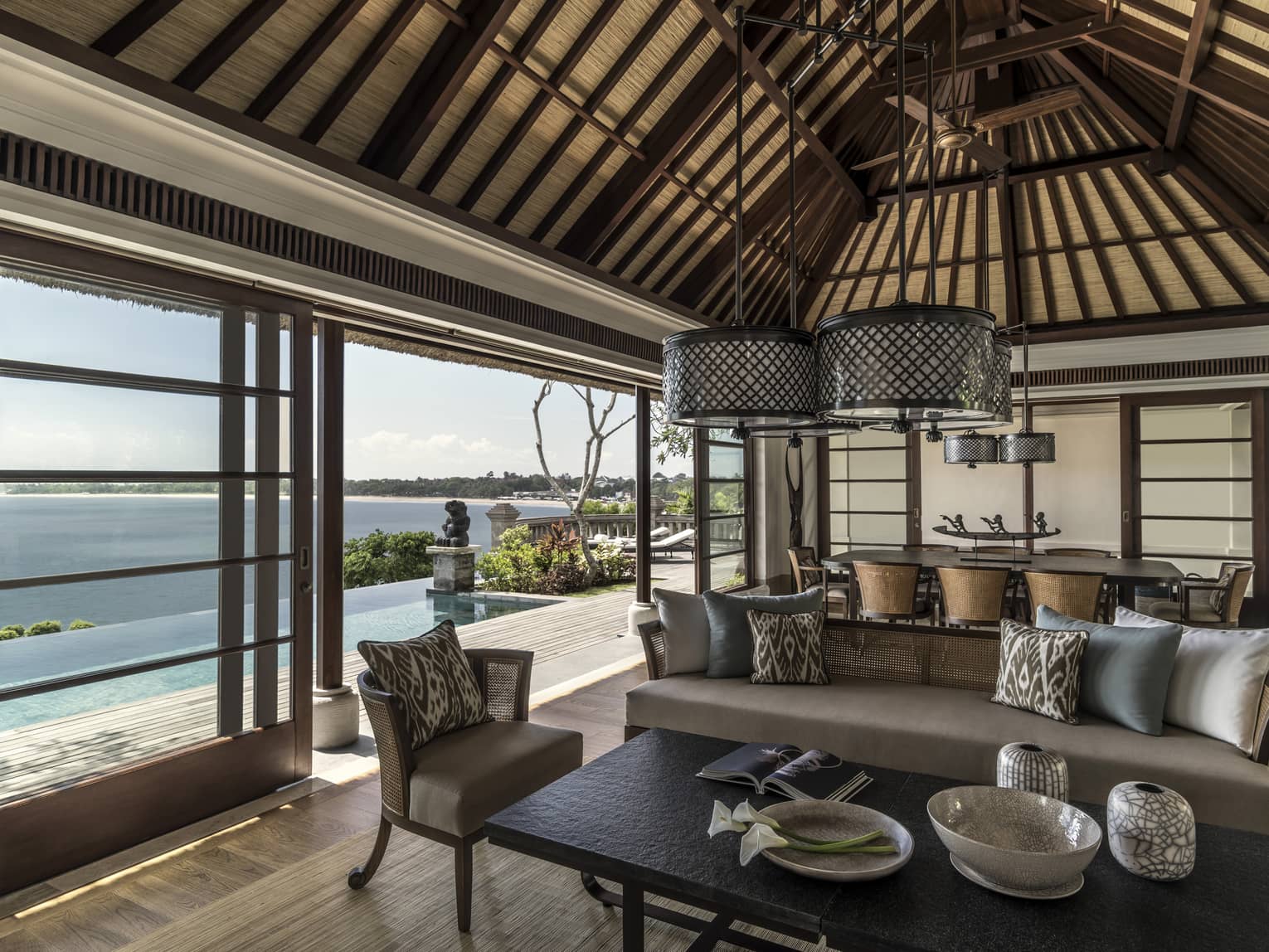 Royal Villa living room with beige sofas, round wicker chandeliers, sliding glass wall to sunny patio