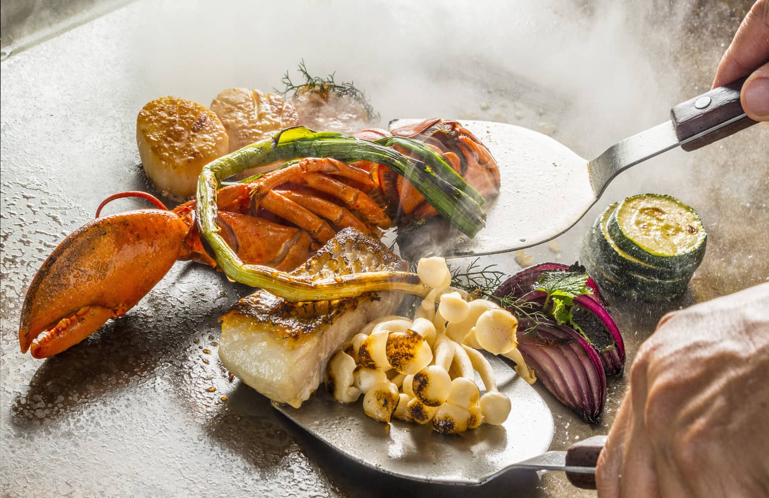 A chef cooks up some teppanyaki on a hot plate