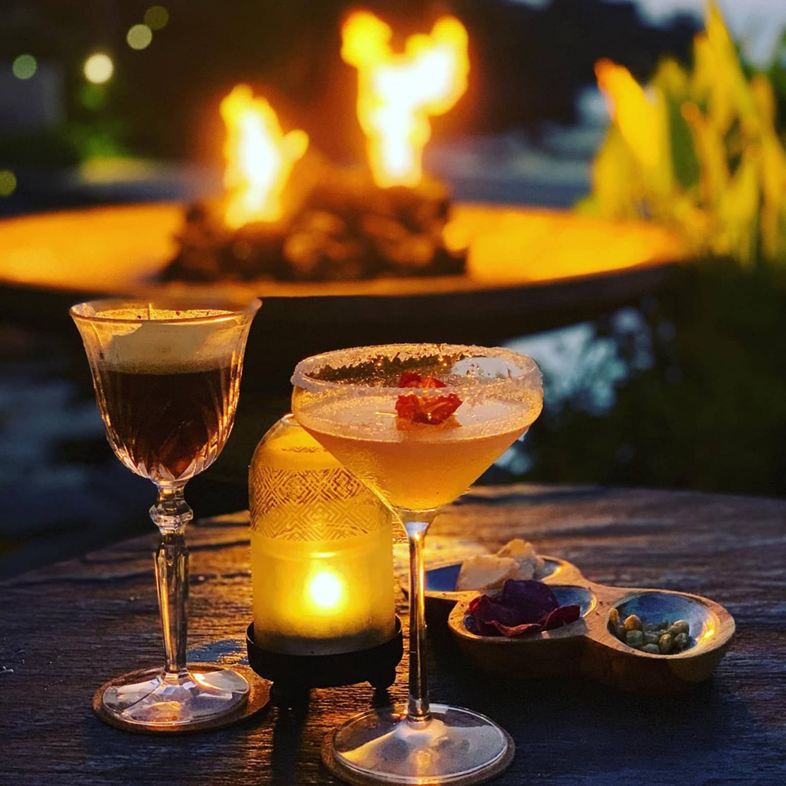 Two cocktails, candle on table near outdoor fireplace