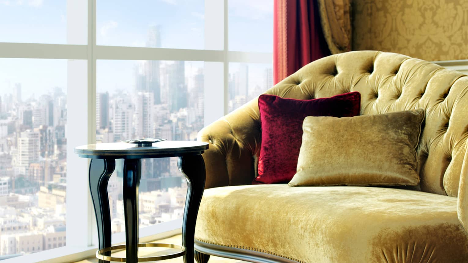 Gold tufted velvet chaise chair with red pillow, small table by sunny window