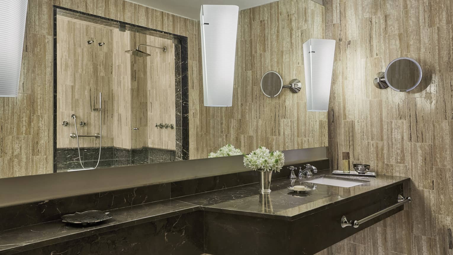 Bathroom with single marbled vanity and sink, woodgrain wallpaper, full-width mirror, lighted wall sconces