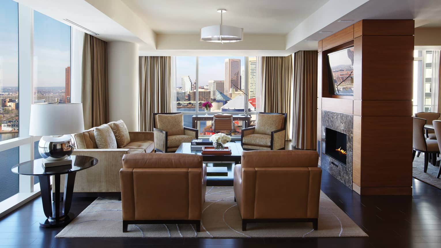 Serene Suite brown leather armchairs, sofa, chairs around gas fireplace, corner windows