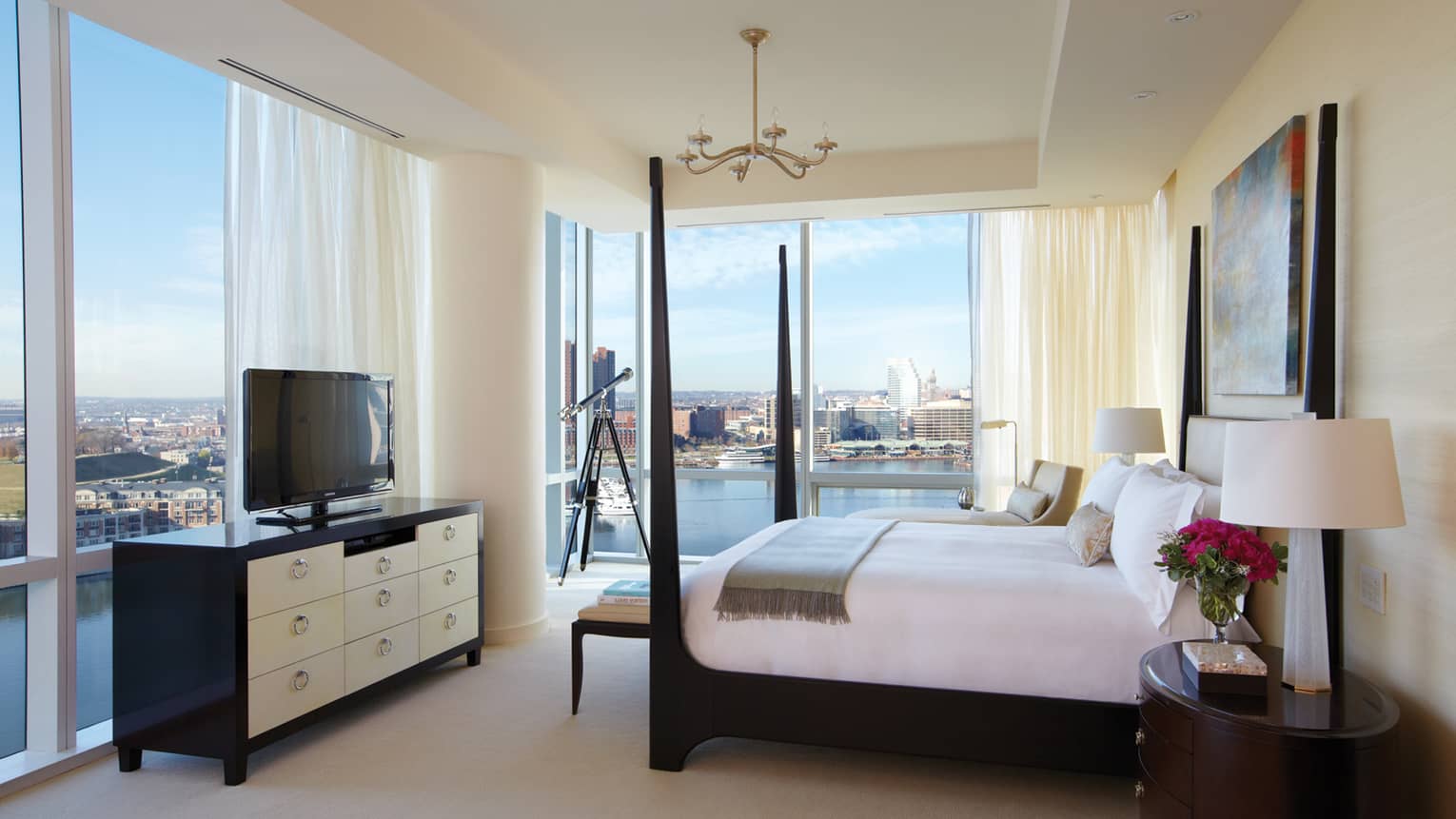 Presidential Suite black poster bed in front of dresser, TV, floor-to-ceiling corner windows