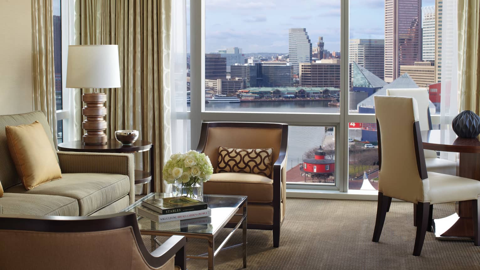 Lighthouse Suite chairs, sofa, coffee table with two books by windows with harbour views