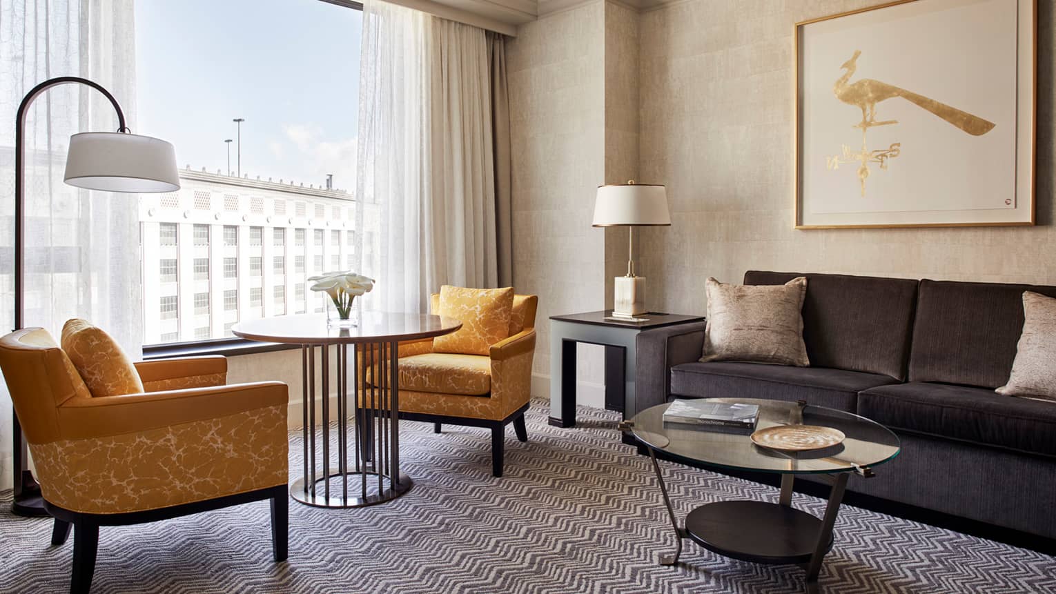 Superior Room living area with two yellow fabric armchairs around round cafe table in front of window, grey sofa