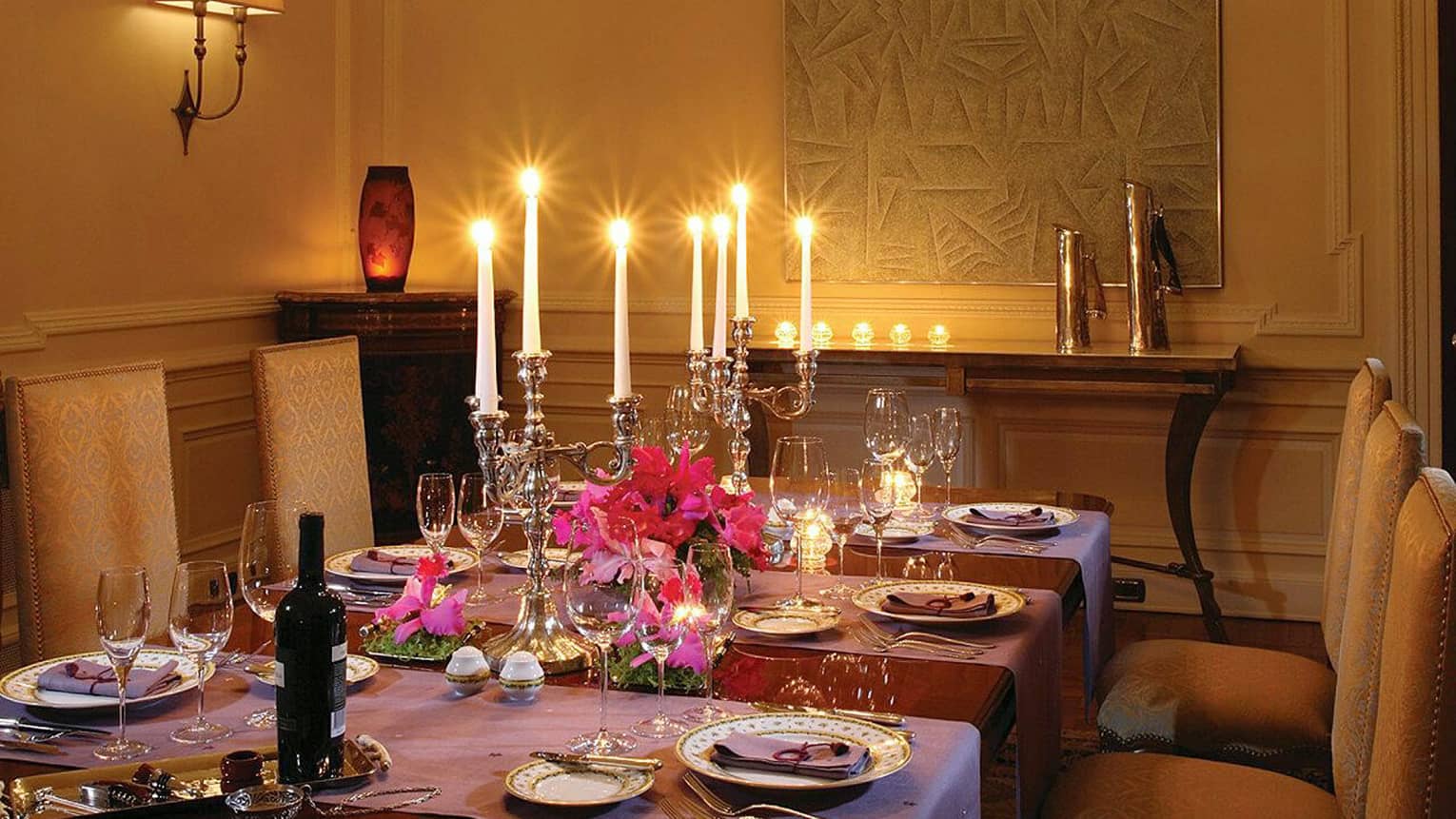 Elegant formal dining table with purple tablecloths, large silver candelabras with glowing candles, gold patterned chairs