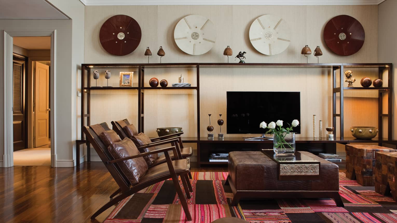 Modern brown leather armchairs and large ottoman with fresh flowers, modern and wood Argentine-inspired art